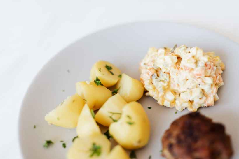 fried cutlet garnished with potato and russian salad